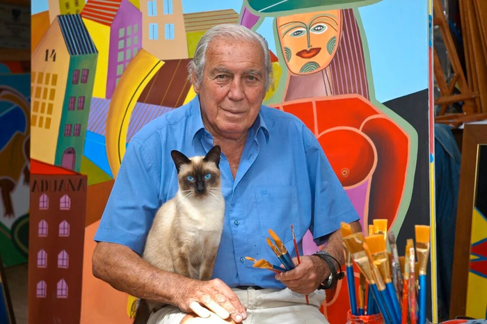 Портрет художника с котом на фоне его работ