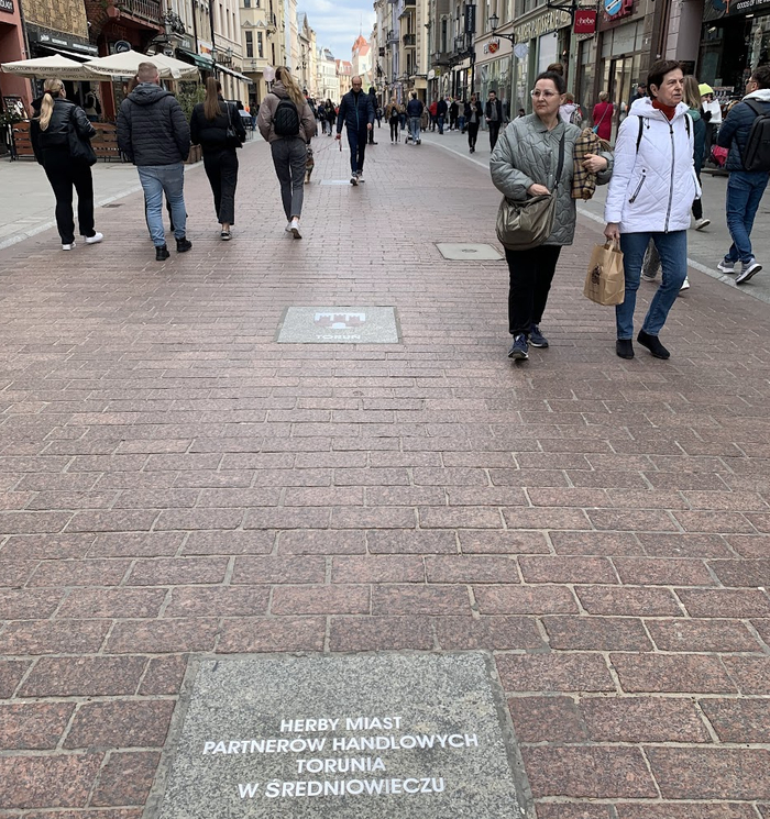 На плите выбито - "Герба городов, торговых партнеров Торуни в средневековье". Ну и на следующий, просматривается герб Торуни - три башни (видили такой у витражной лавки).