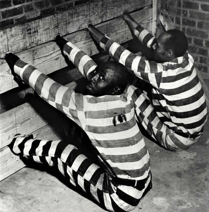 На фотографии чернокожие заключенные примеряют на себе так называемое дисциплинарное наказание, США, 1937 год