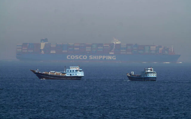 Две традиционные лодки доу проплывают мимо большого контейнеровоза в Ормузском проливе, 19 мая 2023 года. (AP Photo/Jon Gambrell)