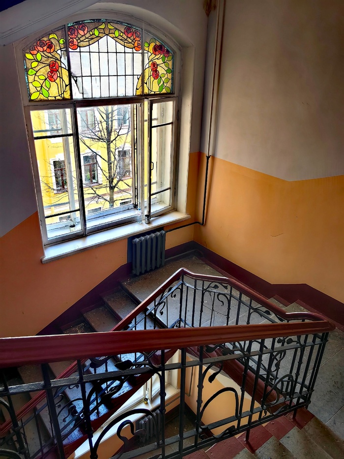 Парадная лестница с коваными перилами и межэтажное окно с частично сохранившимся витражом с розами. Фото А. Шаталкина.