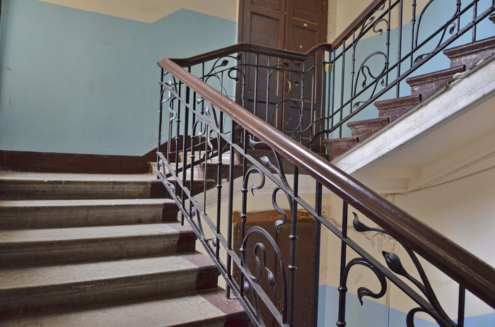 Парадная лестница с коваными перилами и межэтажное окно с частично сохранившимся витражом с розами. Фото А. Шаталкина.